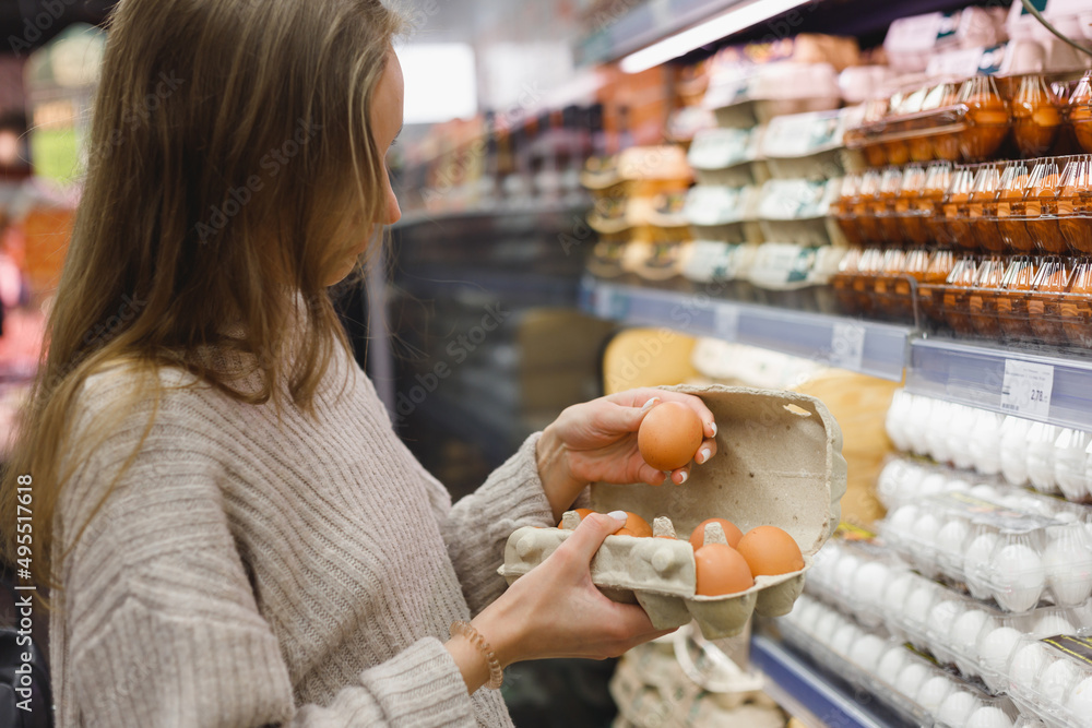 Woman chooses chicken eggs in a farm food store. Food consumption, Easter