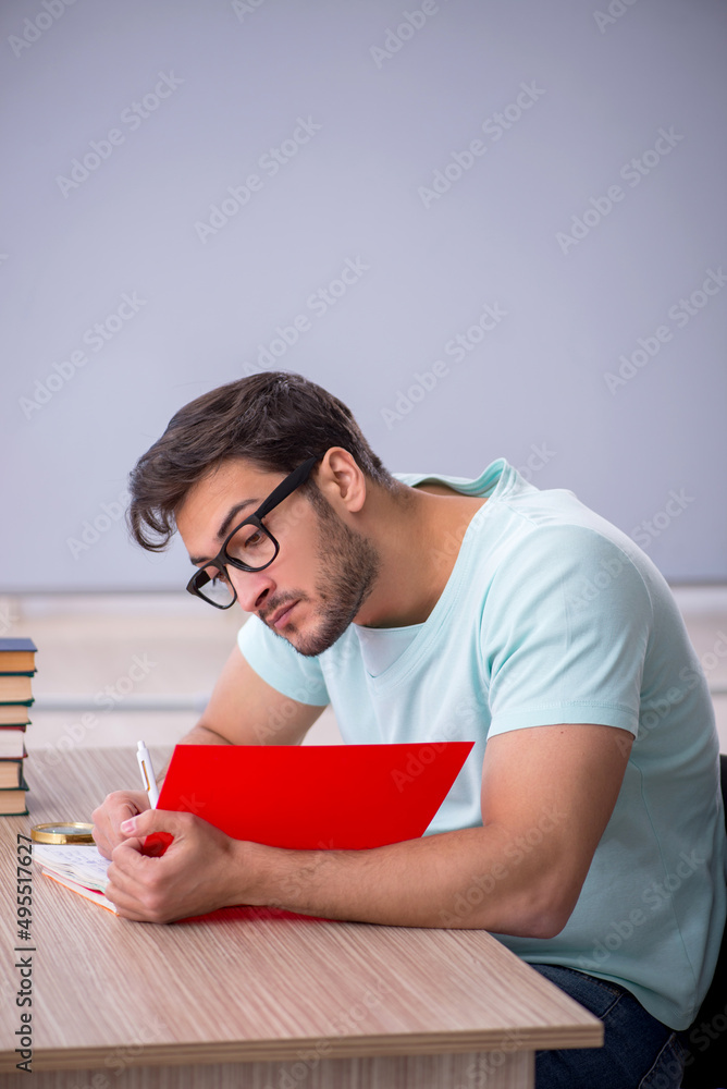 Obraz premium Young male student preparing for exams in the classroom