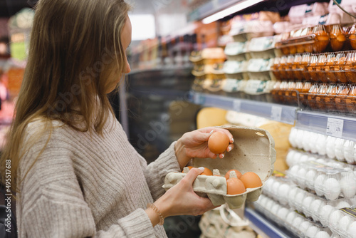 Obraz na płótnie Woman chooses chicken eggs in a farm food store. Food consumption, Easter w salonie