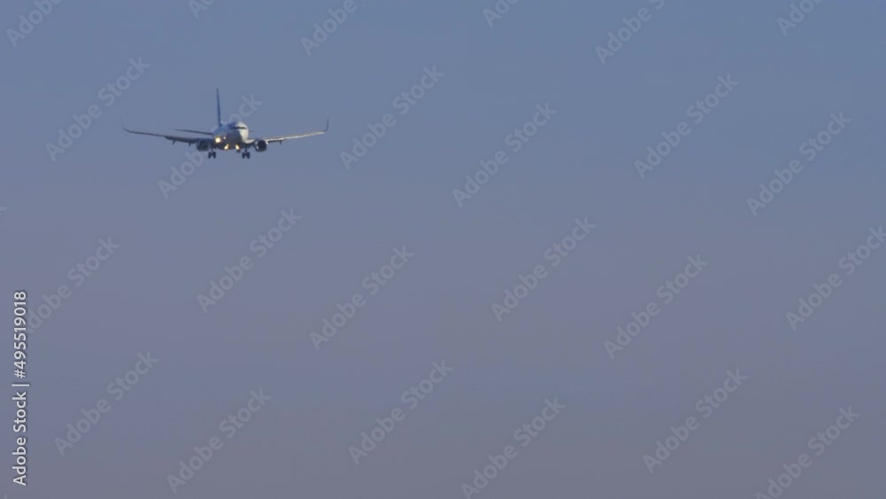Jet passenger plane is approaching to land, front view. Long shot, the airliner is flying, descending. Air industry, travel and tourism concept Jet passenger plane is approaching to land, front view. Long shot, the airliner is flying, descending. Air industry, travel and tourism concept