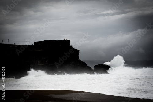 Lighthouse of Nazare with the big waves crashing at the rocks. Lighthouse of Praia do Norte - Nazare - Portugal