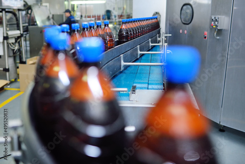 Plastic beer bottles on a conveyor belt in the background of a brewery