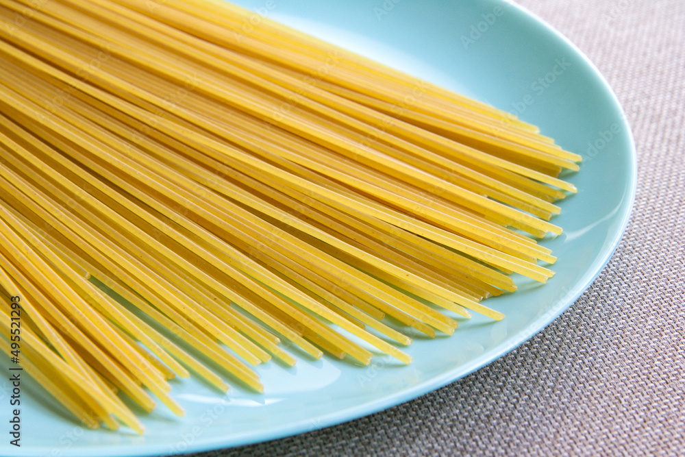 raw wheat spaghetti on a turquoise plate, standing on the table