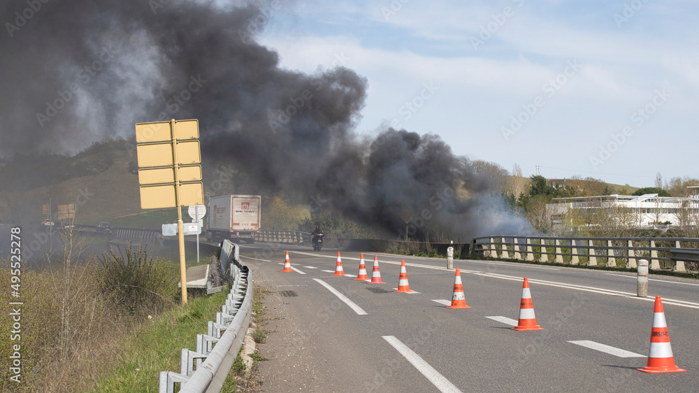 Vehicules on a fast lane, driving in a cloud of black smoke