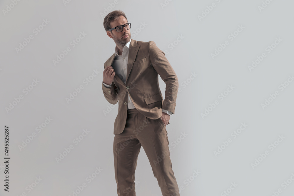 attractive businessman looking back, over shoulder and fixing his suit attractive businessman looking back, over shoulder and fixing his suit