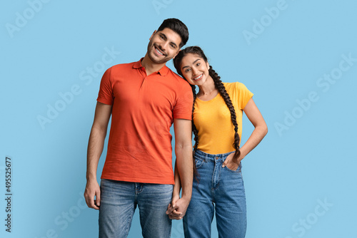 Portrait of happy middle eastern couple holding hands and looking at camera