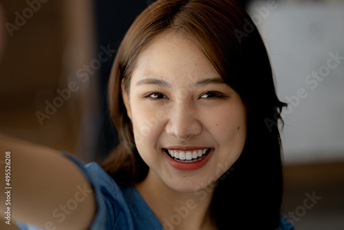 Close-up of Asian woman's face, woman looking at camera as if chatting video call with interlocutor via device. Concept of using technology to communicate through the Internet.