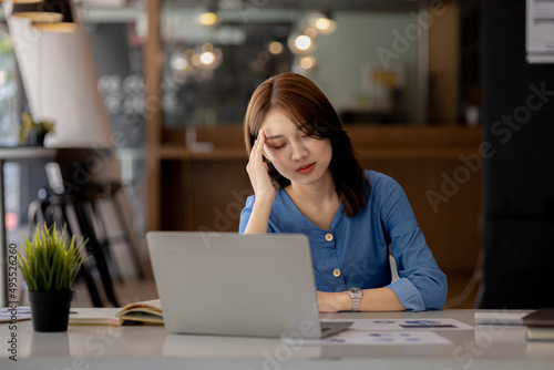 Beautiful Asian woman working in an office, she is a businesswoman who owns a company, she has a headache due to long and large paperwork leaving her tired and dizzy. The concept of sickness from work