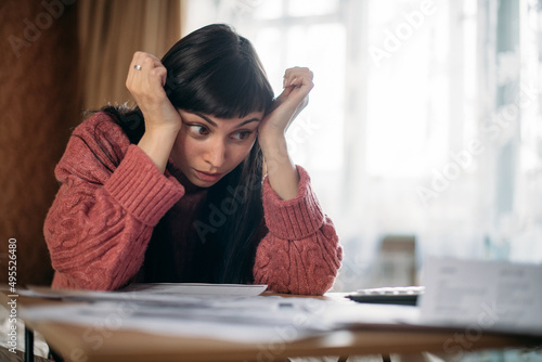 Sad woman holding her head over utility bills. The concept of rising prices for heating, gas, electricity.