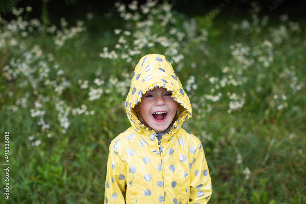 Funny little girl in a yellow raincoat on a background of forest Funny little girl in a yellow raincoat on a background of forest