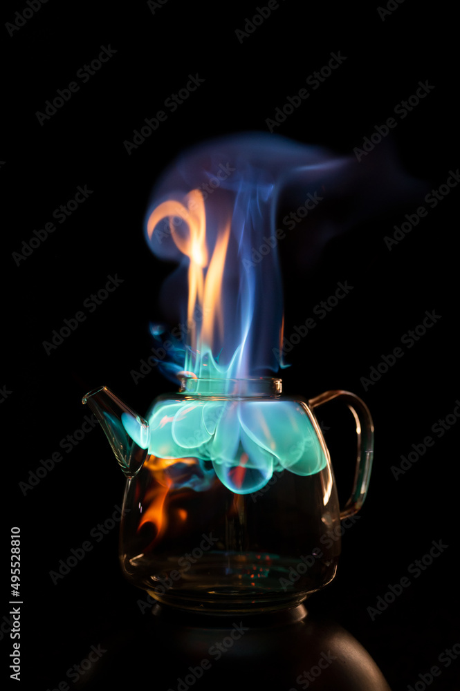 Fire within a see through glass tea pot showing beautiful orange and blue flames inferno giving the idea of substance or alcohol abuse.