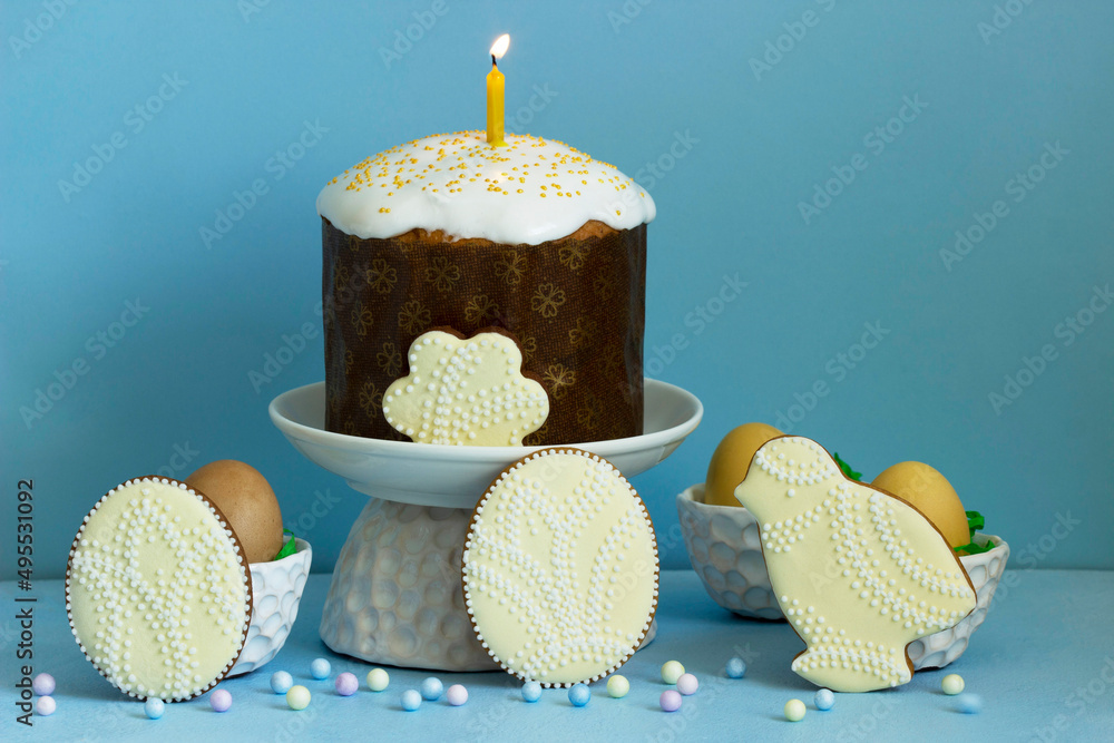 Easter composition, traditional Easter cake, colored eggs and gingerbread on a blue background.