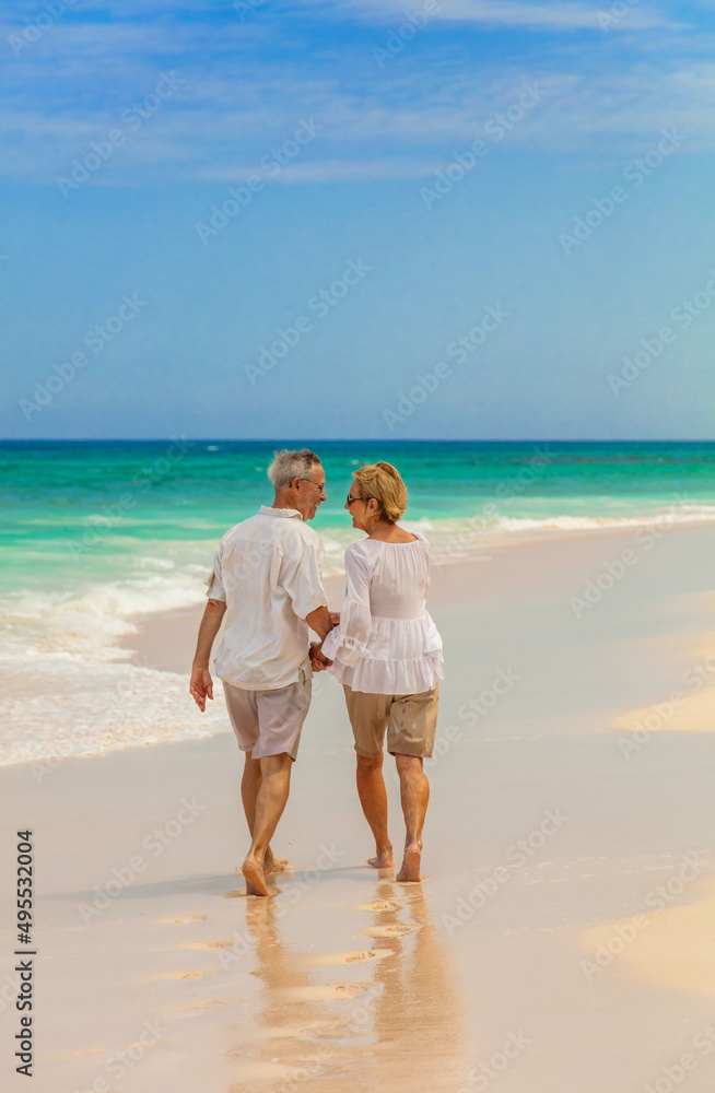 Affectionate senior couple walking on tropical beach Bahamas Affectionate senior couple walking on tropical beach Bahamas