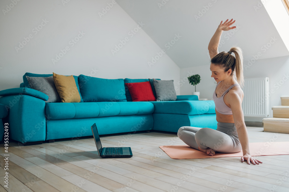 Woman training at home while using a laptop Woman training at home while using a laptop