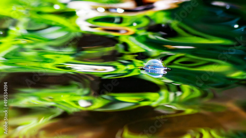Colorful abstract background of a bubble floating in a pond reflecting bright green color