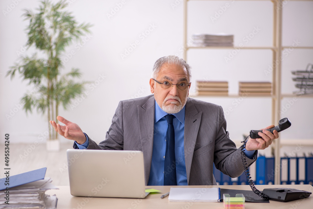 Old male employee working at workplace Old male employee working at workplace
