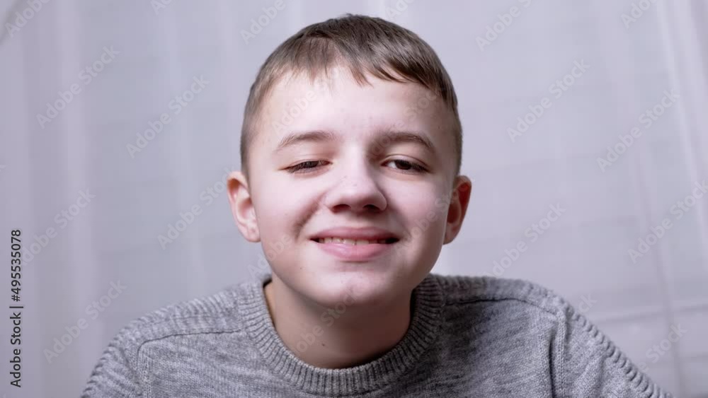 Portrait of Smiling Happy Laughing Boy Looking at Camera. Face of a teenager is close-up. Smile. A beautiful caucasian child opens his mouth, shows teeth, squints blinks his eyes. Child in the room. Portrait of Smiling Happy Laughing Boy Looking at Camera. Face of a teenager is close-up. Smile. A beautiful caucasian child opens his mouth, shows teeth, squints blinks his eyes. Child in the room.