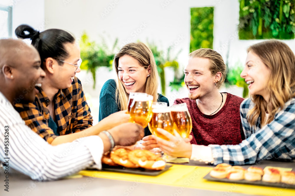 Happy smiling young friends enjoying and toasting beer pint on happy hour at pub - Friendship concept with multiracial people having fun together. Happy smiling young friends enjoying and toasting beer pint on happy hour at pub - Friendship concept with multiracial people having fun together.