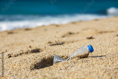 Garbage pollution of the planet. Empty plastic bottle on the beach sand. Consequences of human life