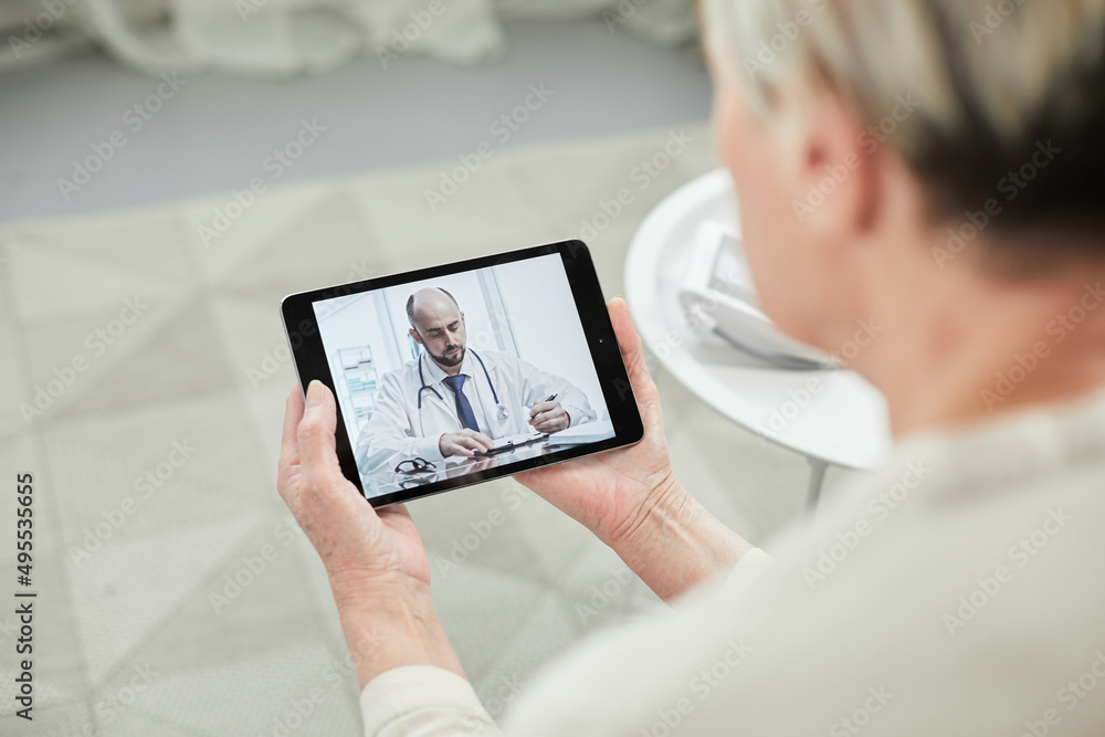 Telemedicine concept, old woman with tablet pc during an online consultation with her doctor in her living room.