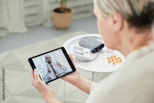 Telemedicine concept, old woman with tablet pc during an online consultation with her doctor in her living room.