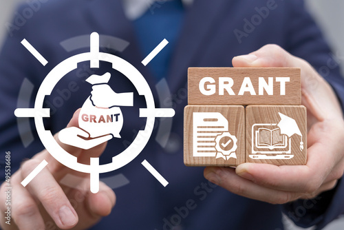 Concept of grants. Application grant. Businessman using virtual touchscreen and holding wooden blocks with grant conceptual presentation. photo