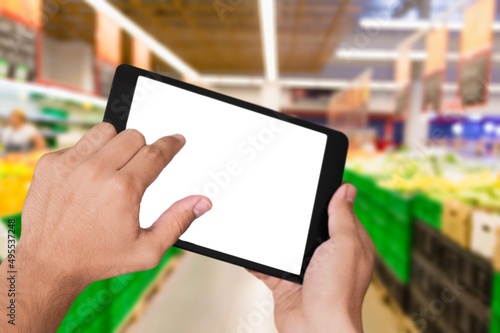Retail management. Worker hands holding tablet on blurred supermarket background