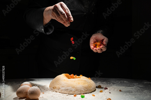 Fotografi women's hands knead dough with candied fruits for easter cakes