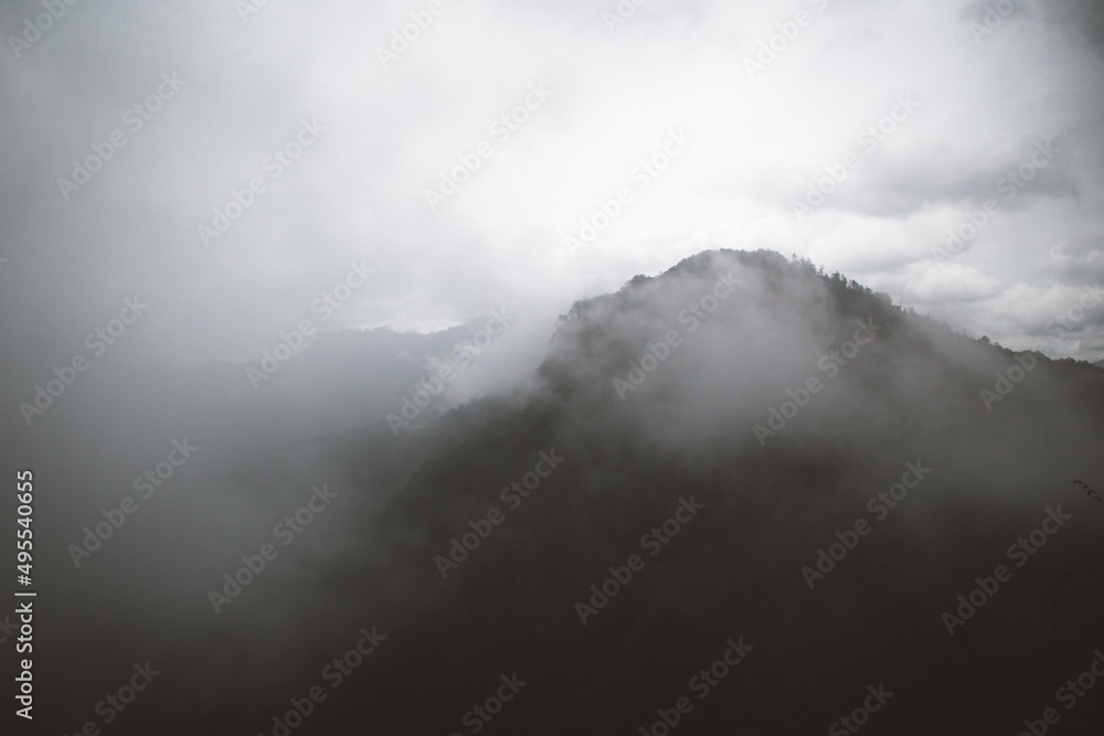 View of a dark mountain range with bright cloudy sky View of a dark mountain range with bright cloudy sky