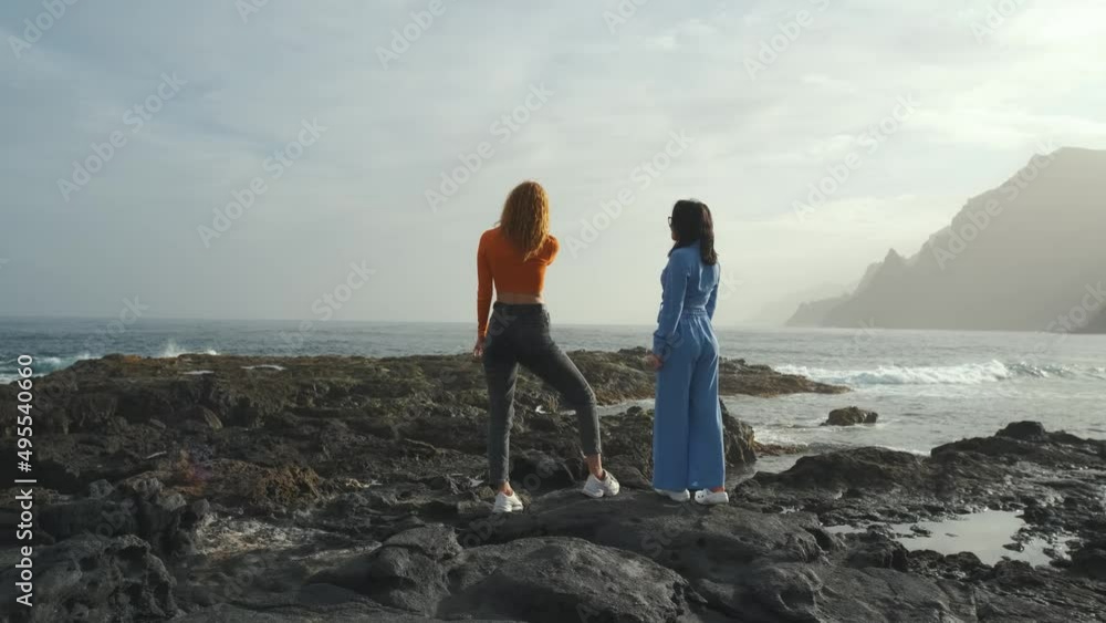 Two beautiful girlfriends walk along the volcanic beach in the north of the Canary island of Tenerife Two beautiful girlfriends walk along the volcanic beach in the north of the Canary island of Tenerife