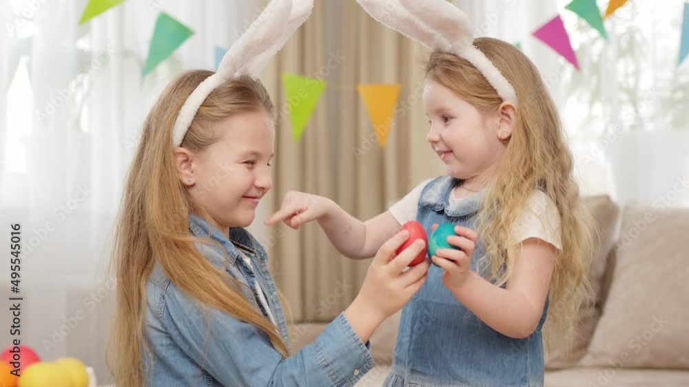 little girls with rabbit ears play with Easter eggs in game of who will break. little girls with rabbit ears play with Easter eggs in game of who will break.