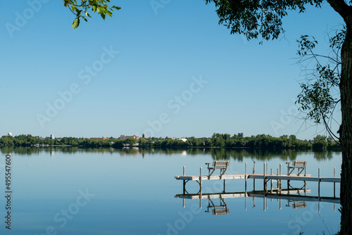 An inviting boat dock is reflected in the glassy water of Lake Irving, the first lake on the Mississippi river, with Bemidji, Minnesota, the 2018 Best Town in Minnesota, seen across the lake. photo