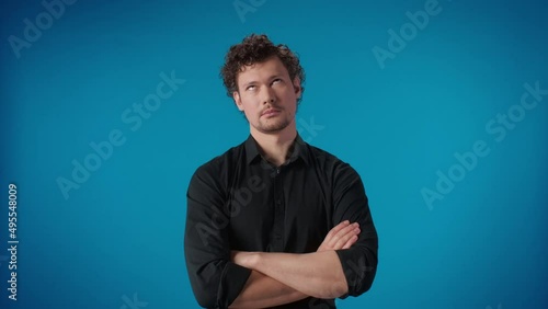 Unsatisfied bearded male in black shirt frowning brows no gesture posing with crossed hands isolated