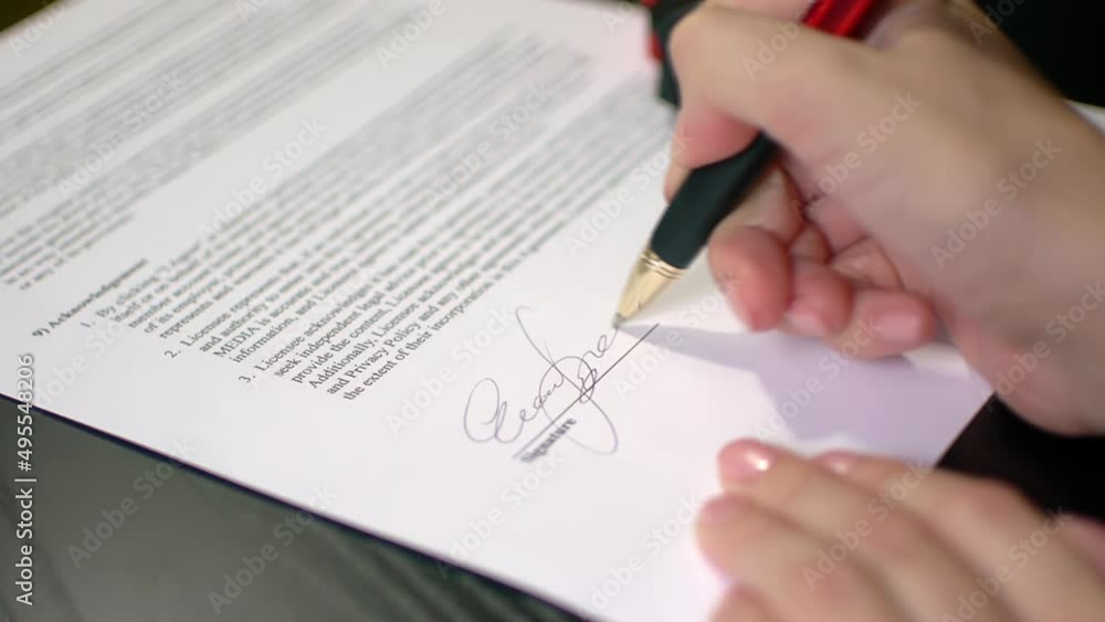 Woman signing an official document Woman signing an official document