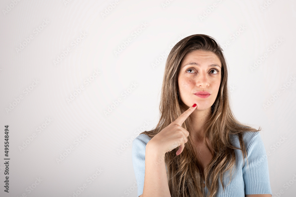 Portrait of a young blonde woman on a white background, with a thoughtful expression, making a decision Portrait of a young blonde woman on a white background, with a thoughtful expression, making a decision