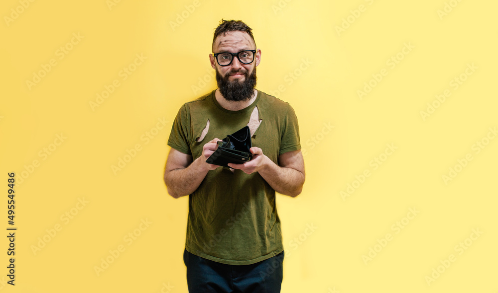 A guy with a dirty face and in torn clothes holds a wallet in his hands and tries to find at least some money. Unemployed Economic crisis. Inflation and bankruptcy. A guy with a dirty face and in torn clothes holds a wallet in his hands and tries to find at least some money. Unemployed Economic crisis. Inflation and bankruptcy.