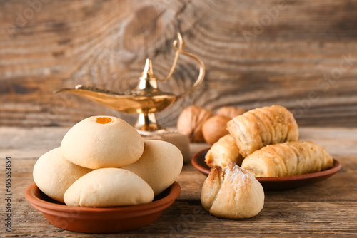 Tasty Eastern sweets with Aladdin lamp on wooden background