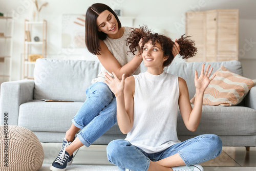 Young woman doing ponytails to her sister in living room