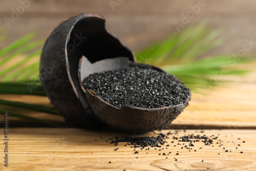 Coconut shells with activated carbon on wooden background
