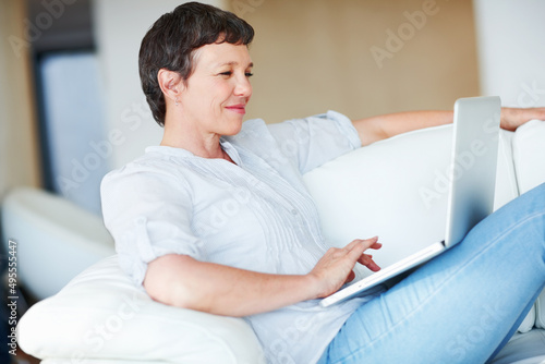 Woman using laptop on couch. Mature business woman sitting on couch using laptop.