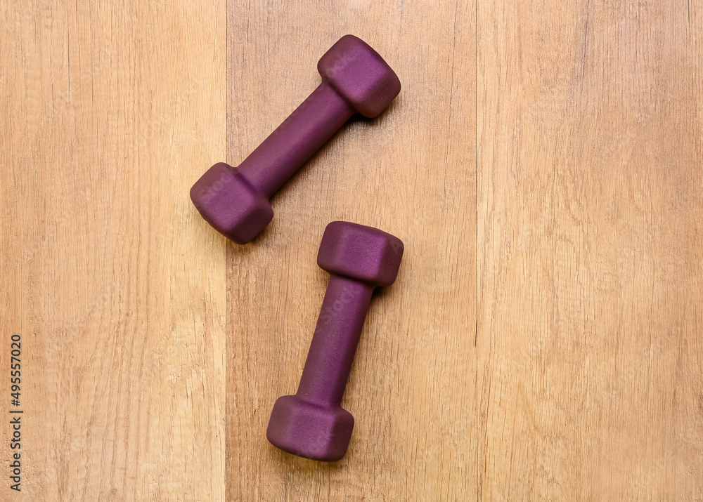 Stylish dumbbells on wooden background Stylish dumbbells on wooden background