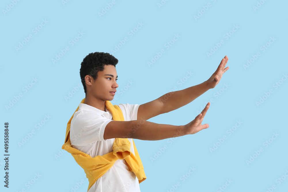 Young African-American man showing stop gesture on blue background. Immunity concept Young African-American man showing stop gesture on blue background. Immunity concept