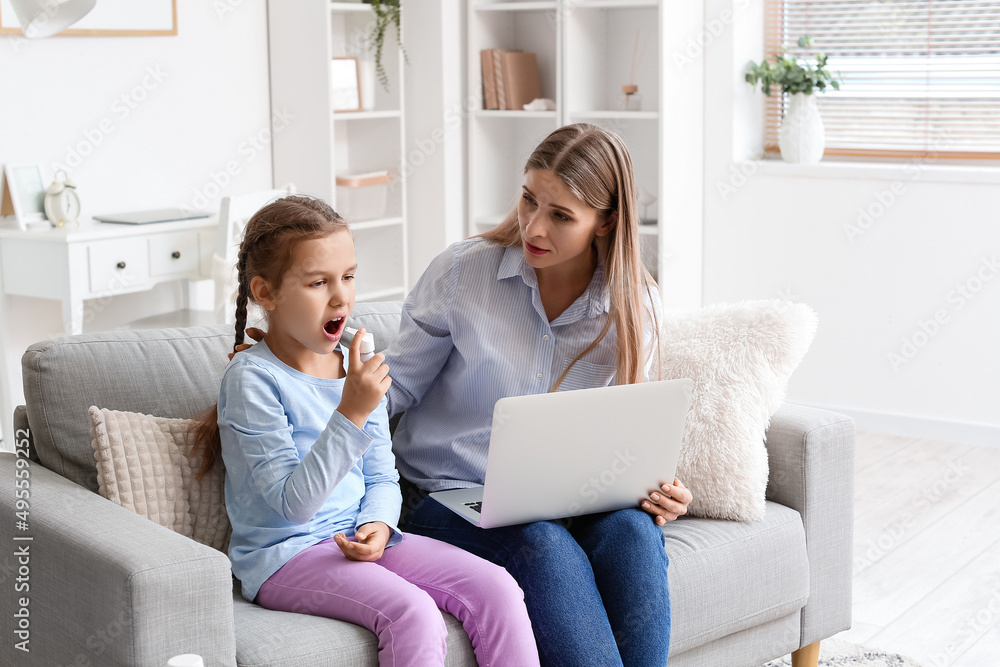 Little girl spraying her sore throat and mother video chatting with doctor at home Little girl spraying her sore throat and mother video chatting with doctor at home