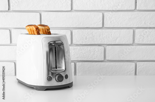 Modern toaster with bread slices on light table