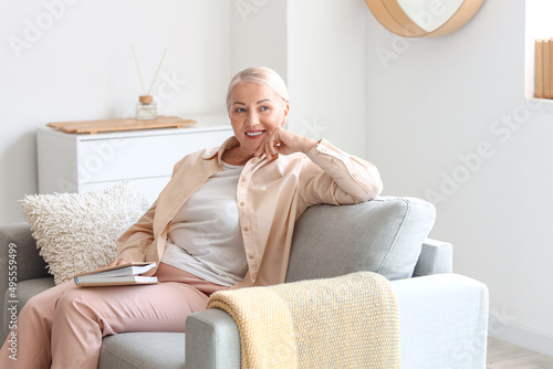 Mature woman with book sitt...