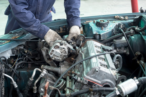 Car mechanic is fixing the engine of a green car.