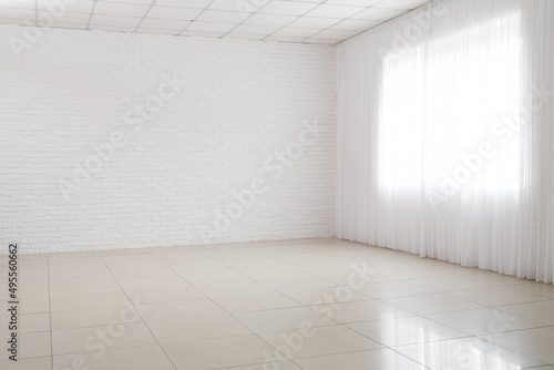 View of big empty room with white brick wall and window