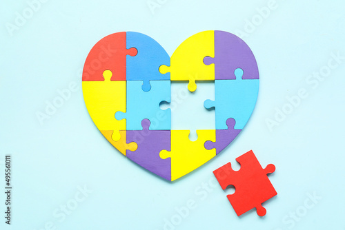 Heart made of puzzle pieces on blue background. Concept of autistic disorder