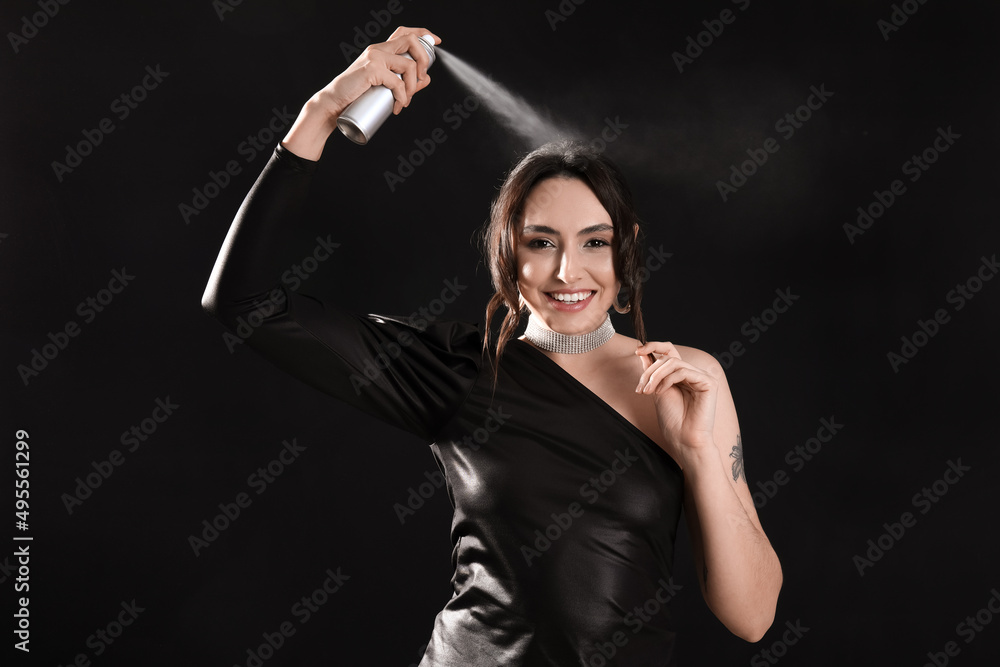 Pretty young woman with hair spray on black background Pretty young woman with hair spray on black background