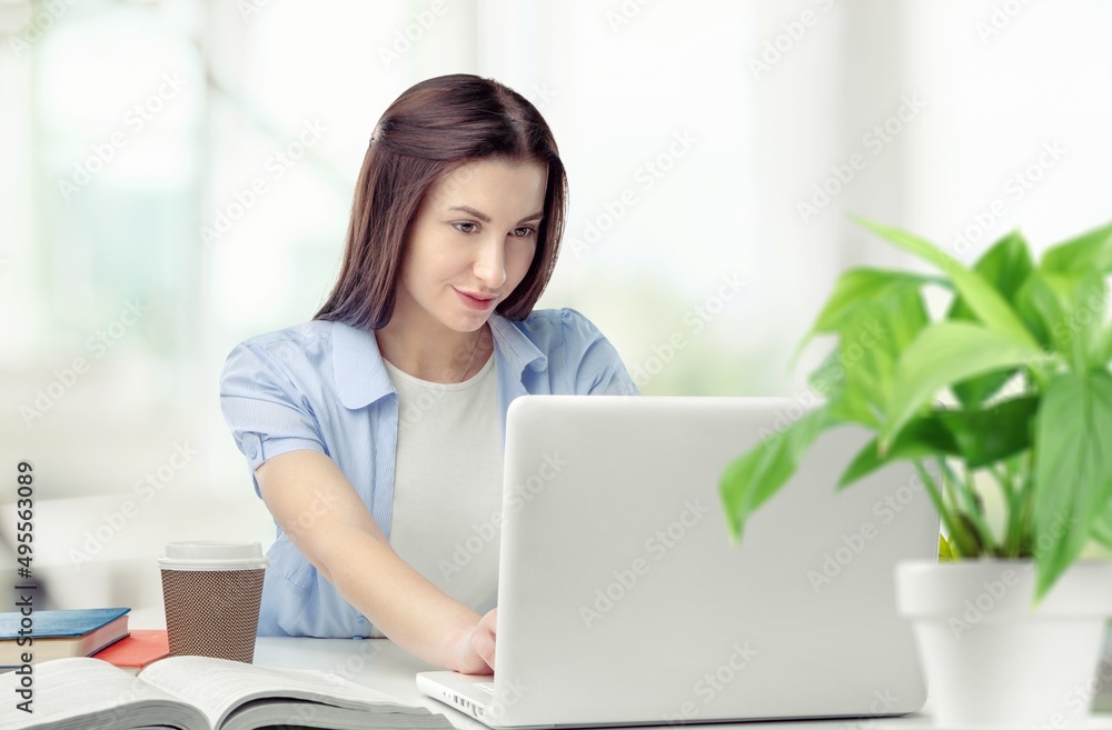 Distance Education. Portrait of smiling student sitting at desk, using laptop Distance Education. Portrait of smiling student sitting at desk, using laptop